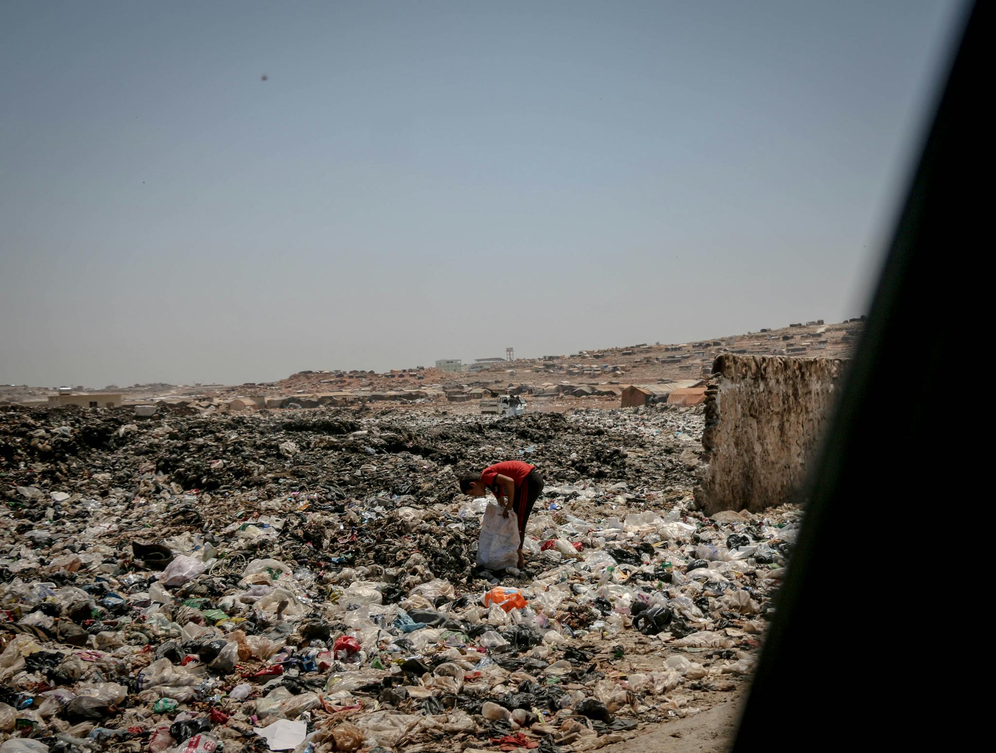 A person navigates a landfill in Idlib, Syria, highlighting the pressing issue of pollution.