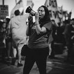 Black and white African American woman in glasses screaming with speaker while visiting political meeting